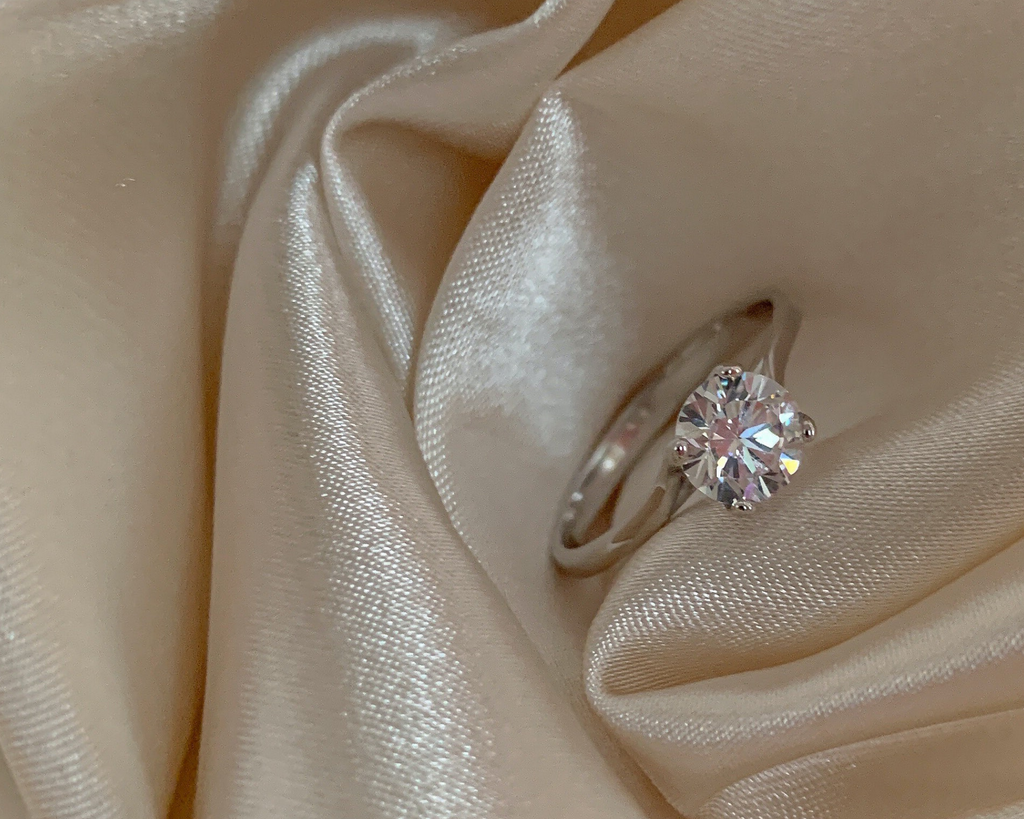 Diamond solitaire engagement on satin sheet